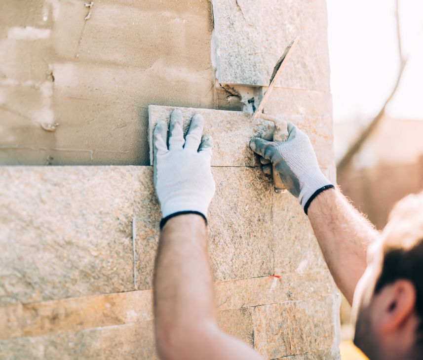 Bauarbeiter setzt Ziegelsteine in die Wand - Bauunternehmen in Lage, NRW
